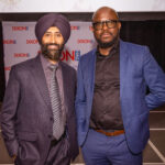 Two men in suits posing together at an event, standing in front of a "DIXON HALL" backdrop.