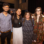 Four people posing together at an event, dressed in stylish and semi-formal attire, smiling at the camera.