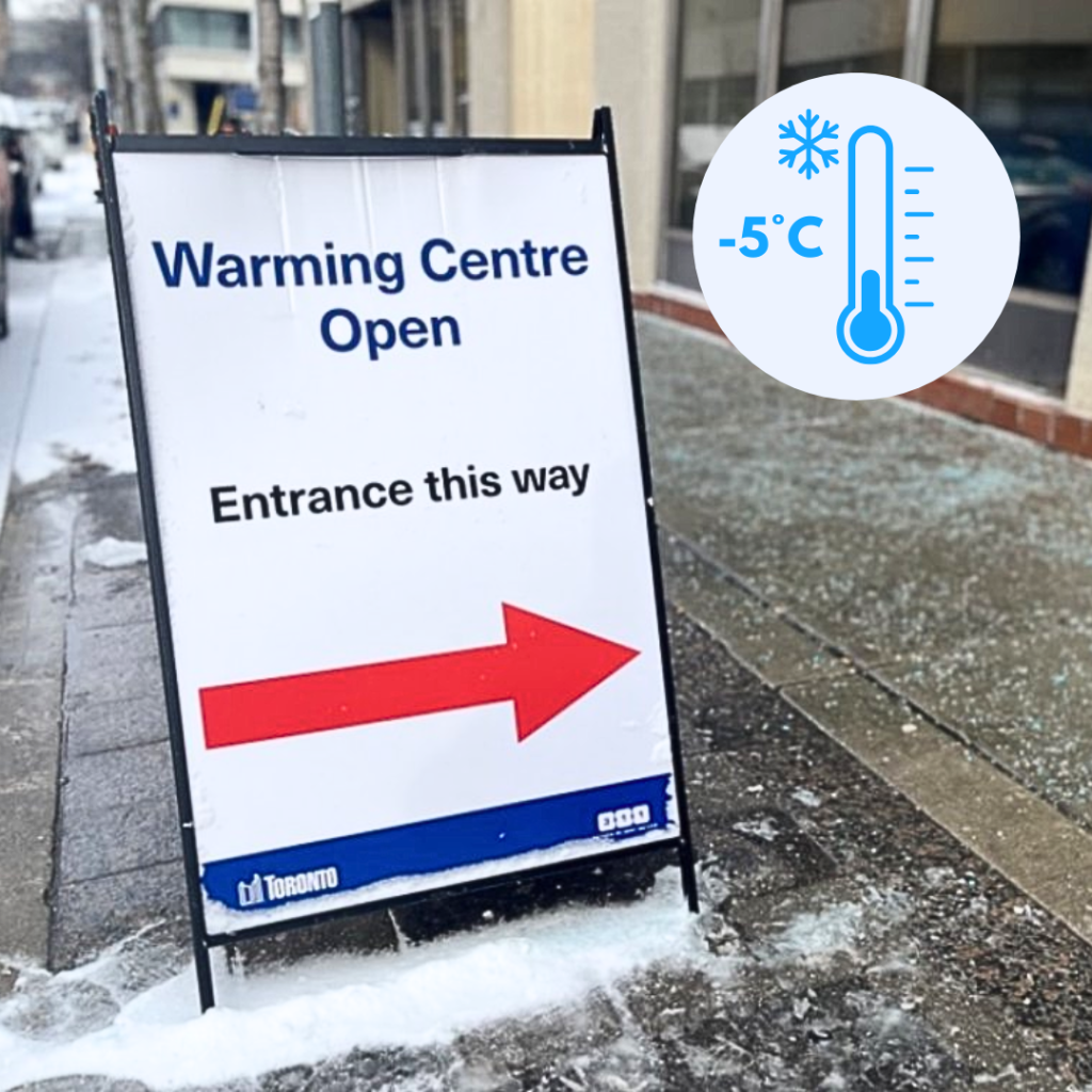 a-sidewalk-sign-reads-warming-centre-open-with-an-arrow-pointing-to-the-entrance-the-sign-includes-the-city-of-toronto-logo-snow-and-ice-are-visible-on-the-ground-and-a-graphic-in-the-corner-shows-a-temperature-of-5-c-
